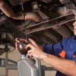 mechanic draining oil underneath a car