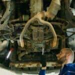 mechanic working on a rusty vehicle at a dealership