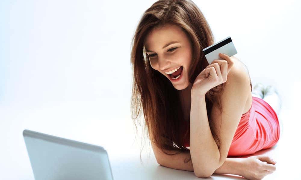 Smiling person holding a credit car shopping on a laptop