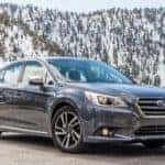 Grey Subaru Legacy near a snowy mountain