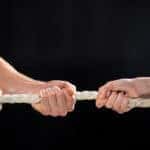 People are shown playing tug-of-war with a rope against a black background.