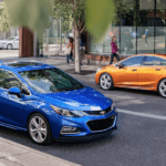 A blue and an orange Chevy Cruze parked on a city street