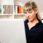 Person holding a credit card near a laptop