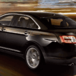 A black 2013 Ford Taurus driving at night in Columbus