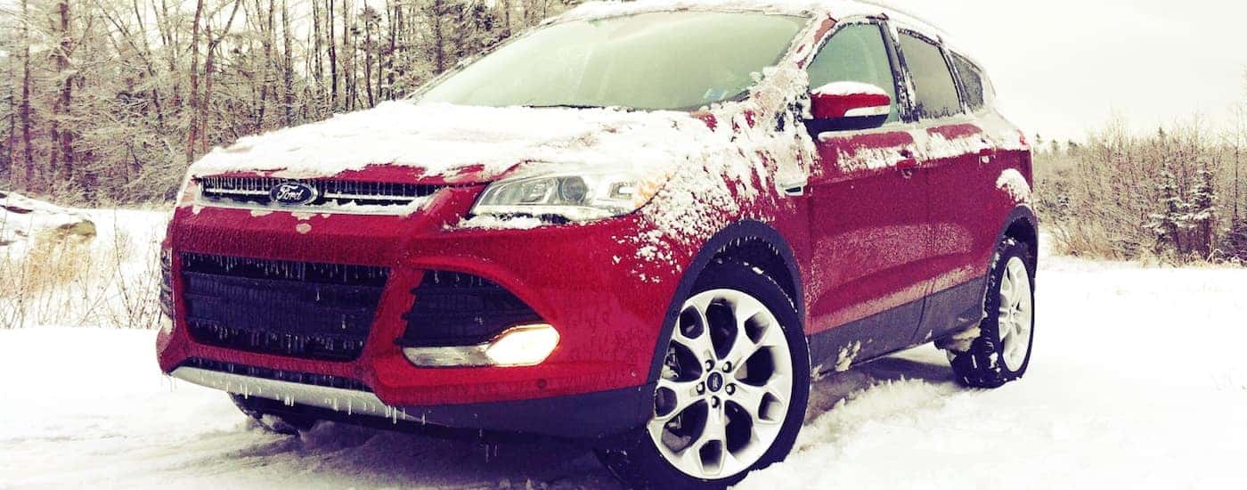 A red 2015 Used Ford Escape covered in snow on a woodland trail