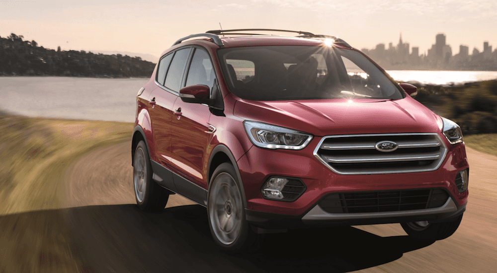 A red 2018 Used Ford Escape driving away from a city and body of water