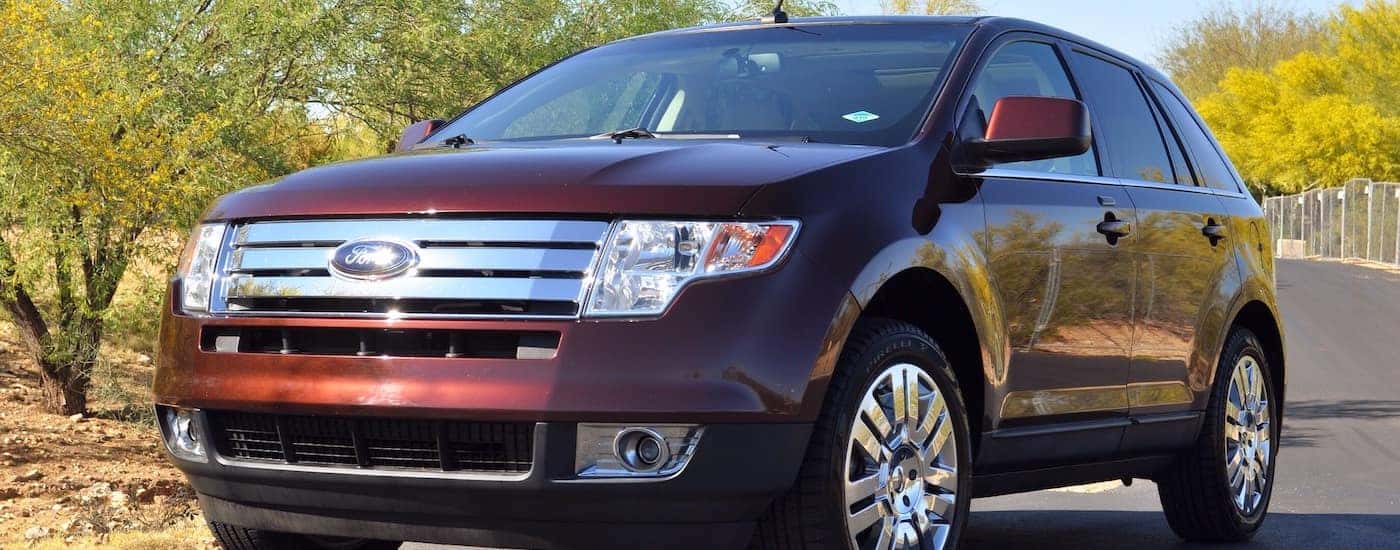 Maroon 2010 Ford Edge on tree-lined road