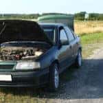 A broken down car on the side =of an empty road