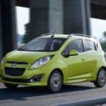 A green Chevy Spark EV travels a local Columbus highway