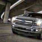 A silver 2018 Ford F-150 is driving under a bridge. The F-150 is one of several options for used Ford trucks in Columbus.