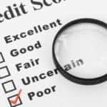 'Poor' is checked off on a list of credit scores with a magnifying glass.