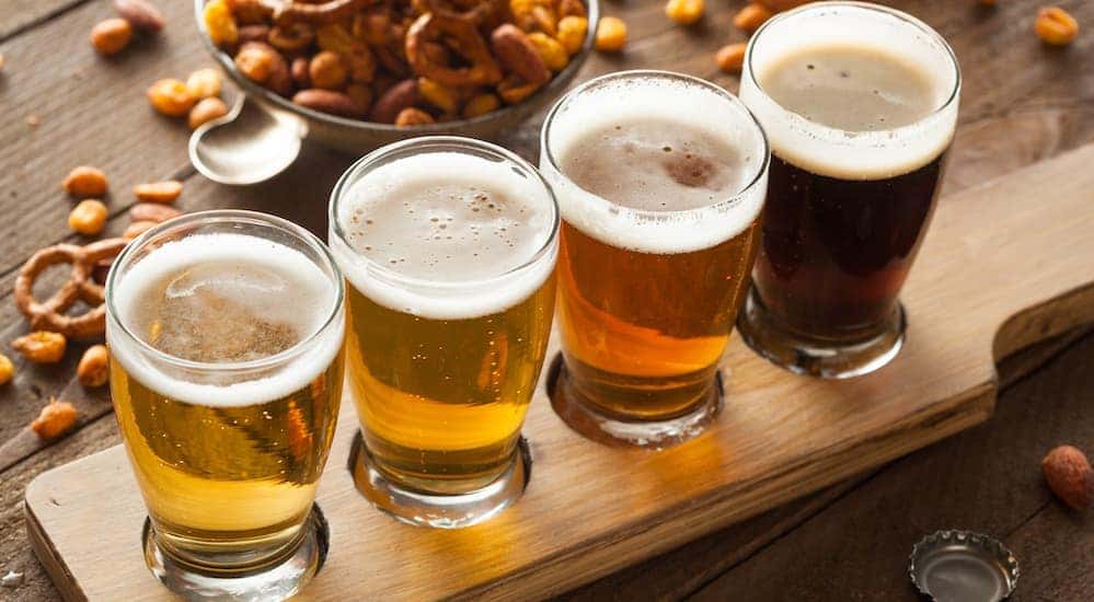 Flight of beer sitting on a wooden table covered in snacks