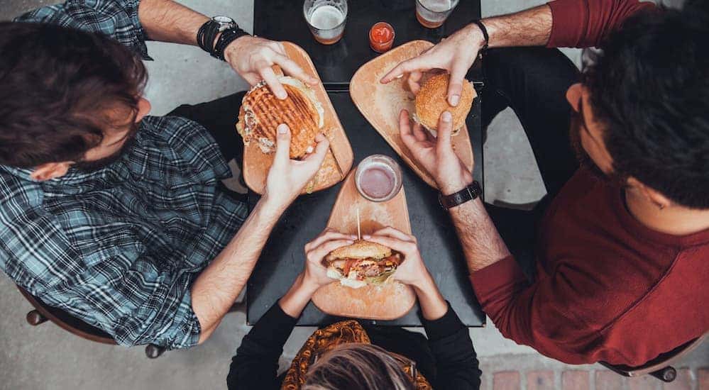 Aerial view of three friends eating sandwiches at a black table