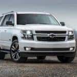 A white 2018 Chevy Tahoe is shown parked on a patch of pavement with leafless trees in the background, auto loans with bad credit, Columbus, OH, you could be approved for this.