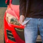 A man with inside out empty pockets is standing front of a car looking for No Credit Car Lots in Indianapolis, IN.