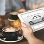 Someone is having a coffee while looking up cars to buy online.