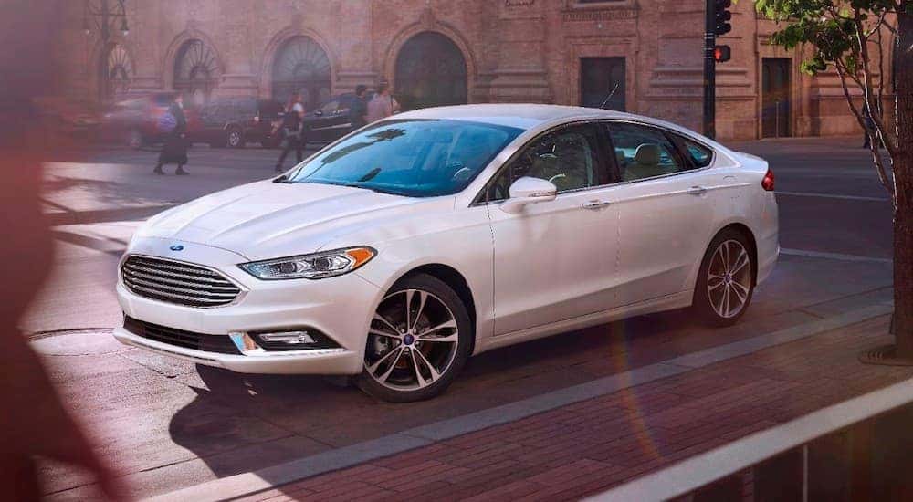 A white 2017 Ford Fusion is parked on a city street.