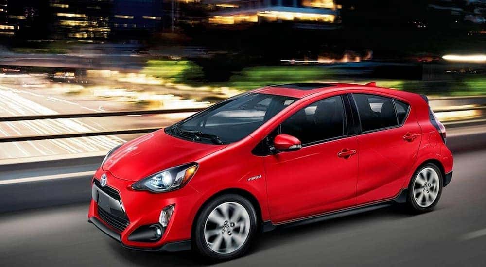 A red 2017 Toyota Prius is driving in the city at night.