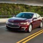 A burgundy 2018 Chevy Malibu, which is a popular used Chevy in Columbus, OH, is driving on a highway.