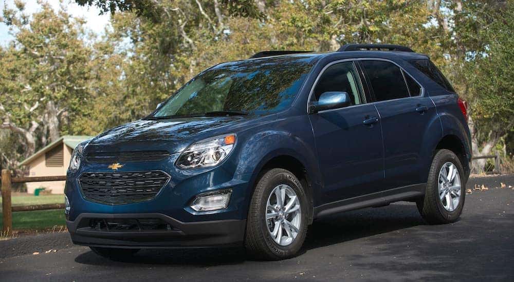 Une Chevy Equinox bleue 2016, qui est une option populaire parmi les SUV Chevy d'occasion à vendre à Indianapolis, IN, est garée à côté d'un parc.