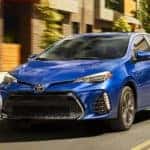 A blue 2019 Toyota Corolla, which is popular among used cars in Columbus, Ohio, is driving past a blurred building.