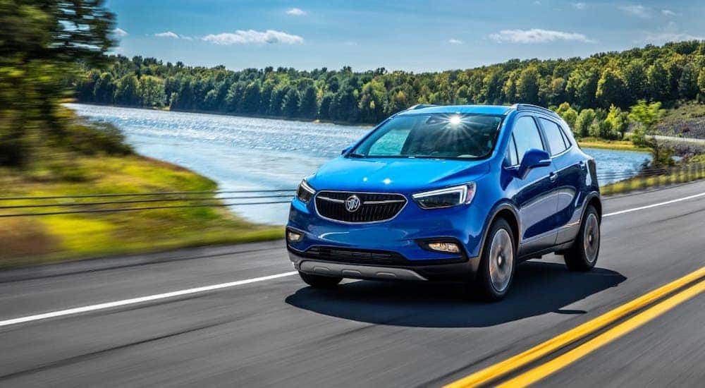 A blue 2019 Buick Encore is driving past a lake.