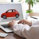 Someone is looking at a red car at an online car dealership from the comfort of their table.