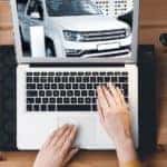 A top-down view shows hands looking at a white truck from an online car dealership.