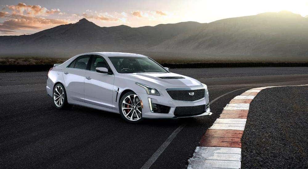 A popular used car in Columbus, Ohio, a white 2018 Cadillac CTS-V, is parked on a track with mountains in the distance.