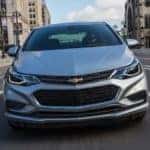 A silver 2017 Chevy Cruze is shown from the front driving on a city street.