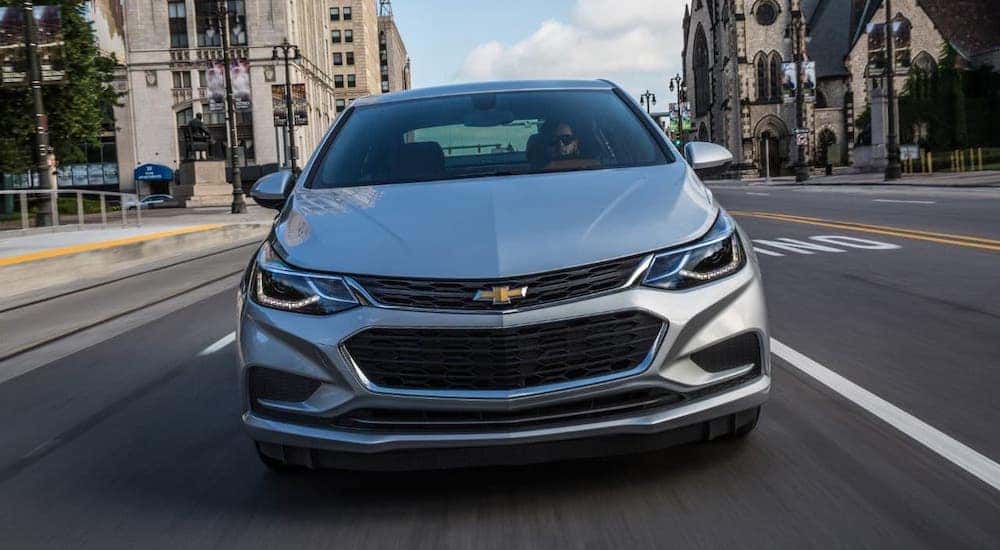 A silver 2017 Chevy Cruze is shown from the front driving on a city street.