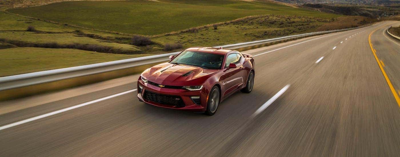 A red 2017 Chevy Camaro SS is driving on an empty highway.