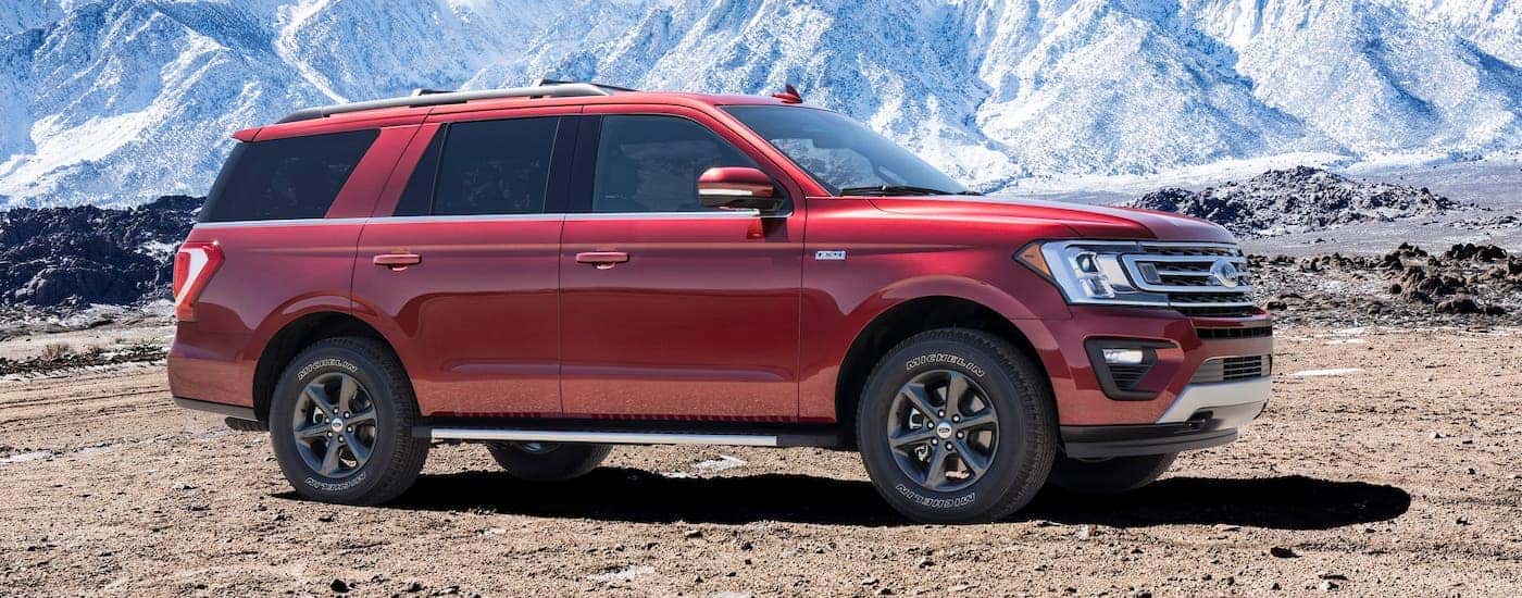 A red 2017 Ford Expedition is parked in front of snow-covered mountains.