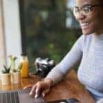 A smiling woman is at a laptop and trying to find cars online.