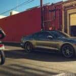 A dark gray 2019 Ford Mustang is parked next to a motorcycle after leaving a used car dealer in Cincinnati.