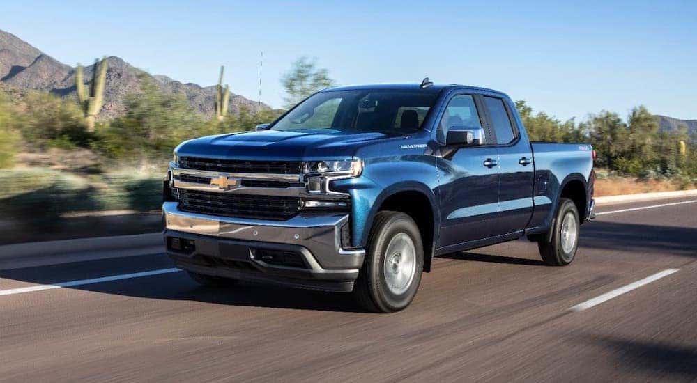 A blue 2019 Chevy Silverado 1500 is driving on a desert highway.