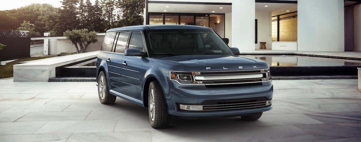 A dark blue 2019 Ford Flex is parked in front of a modern home.