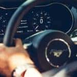 A closeup shows hands on the steering wheel of one of the best used cars in Indianapolis, a 2018 Ford Mustang.