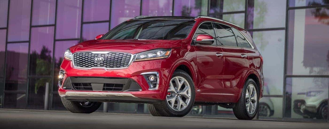 A popular used car in Columbus Ohio, a red 2019 Kia Sorento, is parked in front of a wall of windows.