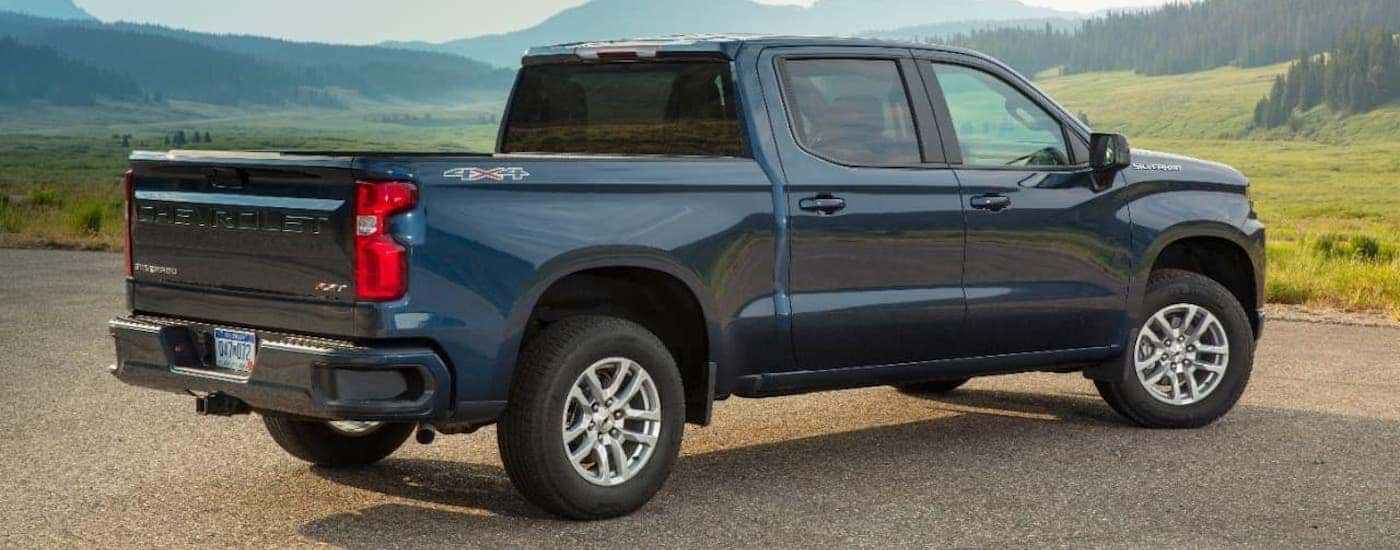 A dark blue 2020 Chevy Silverado is parked facing away towards a meadow.