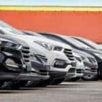 A row of cars is shown outside of a dealership.