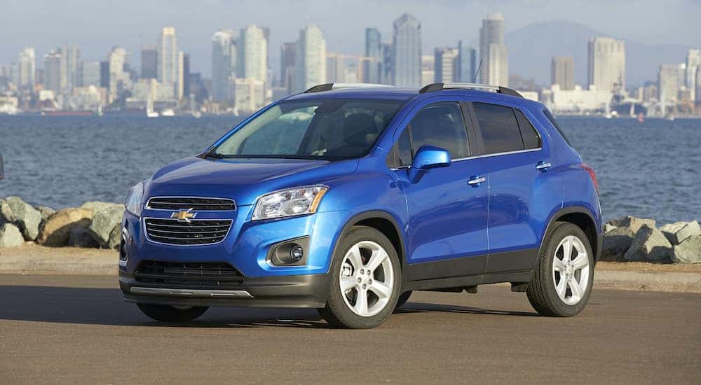 A blue 2016 Chevy Trax is parked in front of a bay.