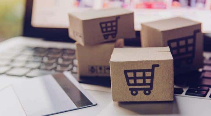 small shopping cart blocks are shown next to a credit card laying on a computer.