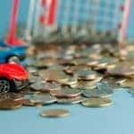 A close up shows a pile of change and two toy cars.