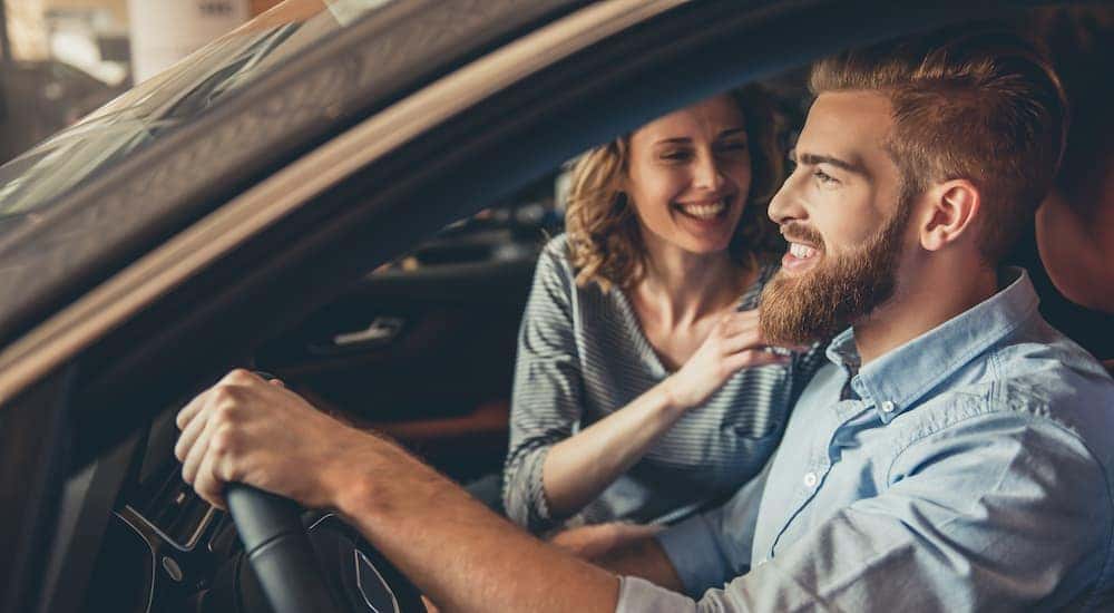 Smiling couple in a pre-owned vehicle while shopping at a used car lot in Indianapolis