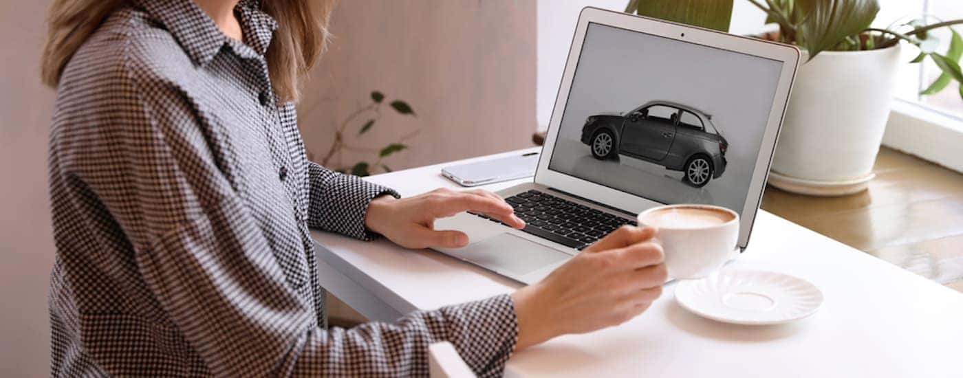 A woman on her laptop is searching for 'used cars for sale near Columbus.'