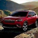 A red 2019 Jeep Cherokee is parked in the mountains after searching for used cars for sale online.