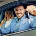 A happy couple is holding a set of keys after learning where to buy used cars.