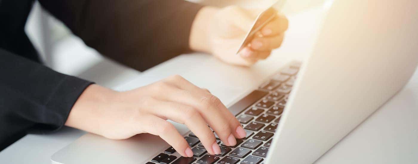 A person is typing credit card information into a laptop.