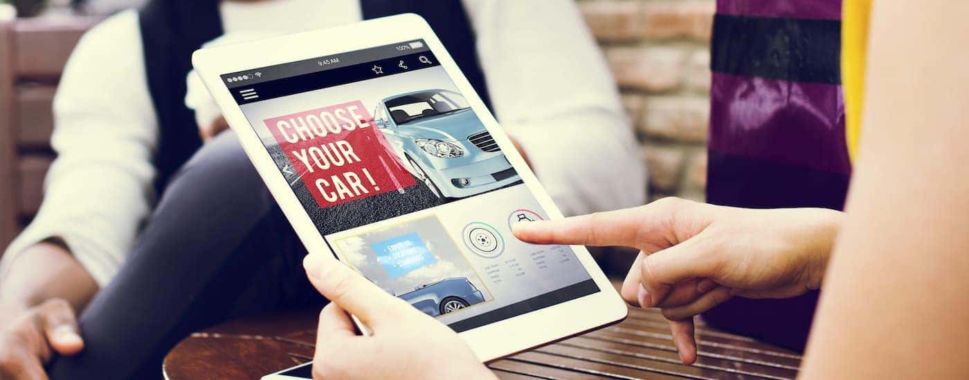 A person is shown using a tablet to look at Columbus online car sales.